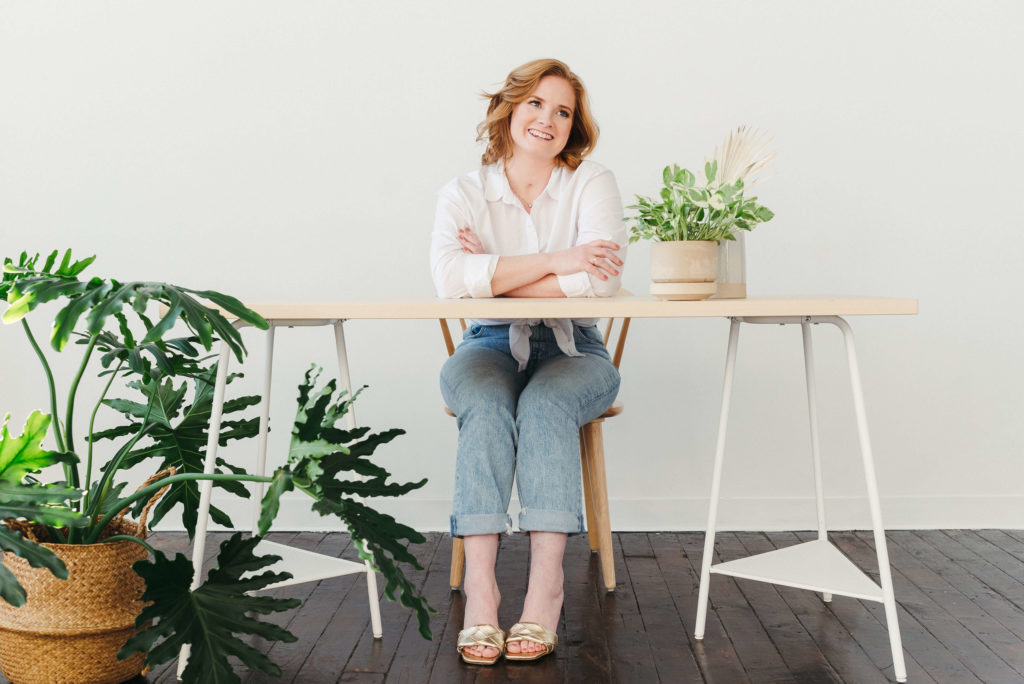 Wedding photographer smiling sitting at desk with houseplants